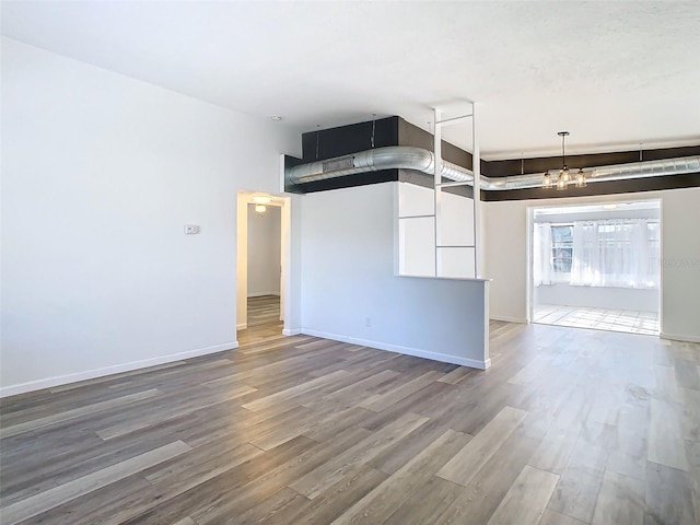 spare room with a chandelier, baseboards, and wood finished floors