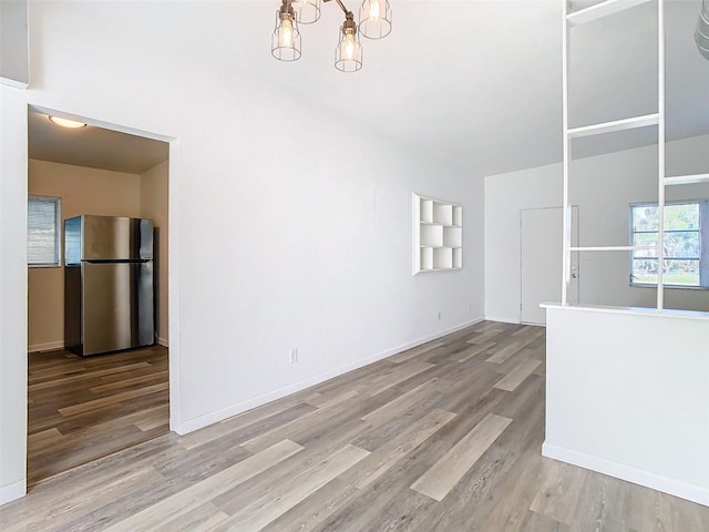 interior space with baseboards, an inviting chandelier, and wood finished floors