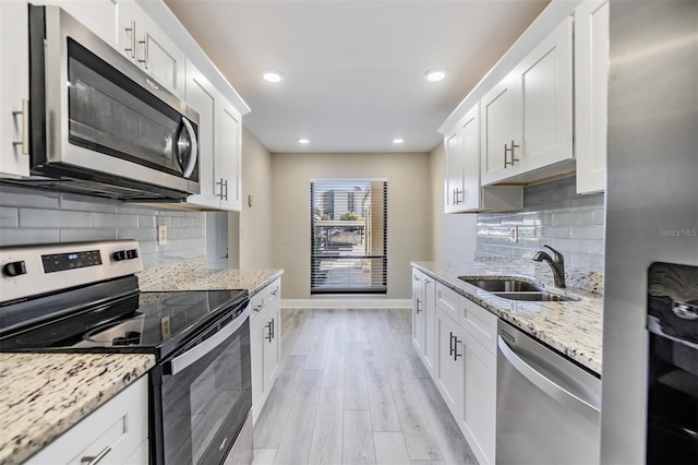 kitchen featuring appliances with stainless steel finishes, light hardwood / wood-style floors, white cabinetry, and sink