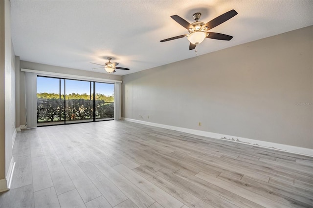 spare room featuring ceiling fan, light wood-type flooring, and a textured ceiling