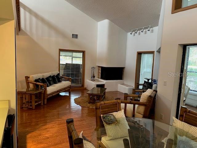 living room with rail lighting, wood-type flooring, a textured ceiling, and a high ceiling