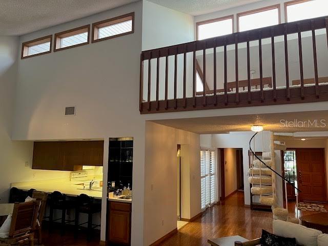 living room featuring a textured ceiling, dark wood-type flooring, a healthy amount of sunlight, and a high ceiling