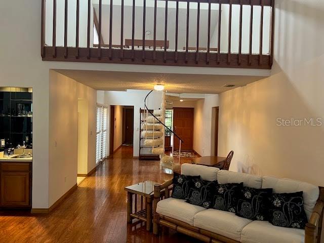 living room featuring dark hardwood / wood-style floors, a towering ceiling, and sink