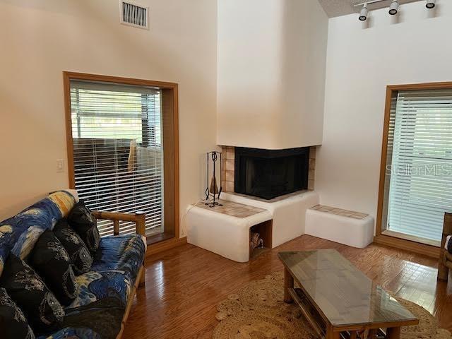 living room featuring a tiled fireplace, hardwood / wood-style floors, rail lighting, and a healthy amount of sunlight