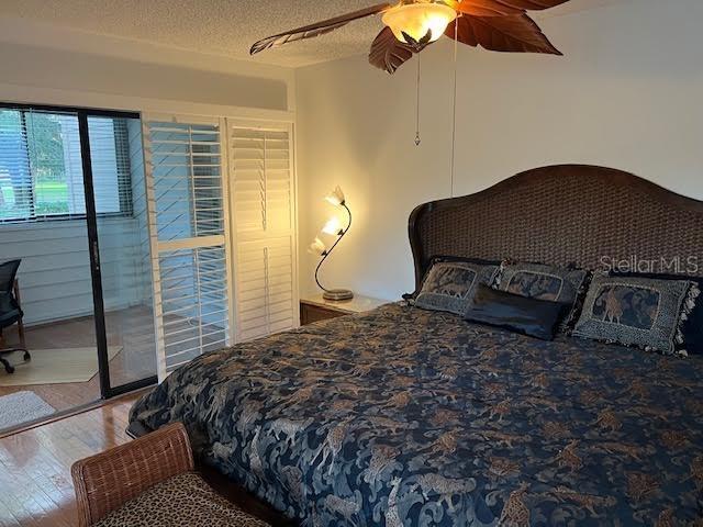 bedroom with access to exterior, a textured ceiling, hardwood / wood-style flooring, and ceiling fan