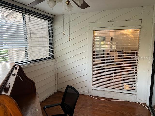 office space with wooden walls, ceiling fan, and hardwood / wood-style flooring