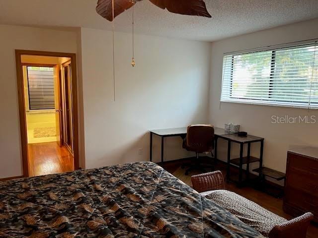 bedroom featuring dark hardwood / wood-style flooring, a textured ceiling, and ceiling fan