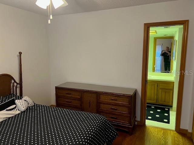 bedroom with ensuite bathroom and dark wood-type flooring