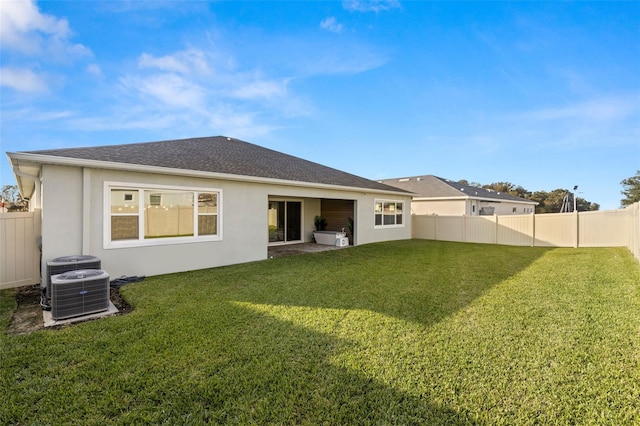 rear view of house featuring cooling unit and a lawn