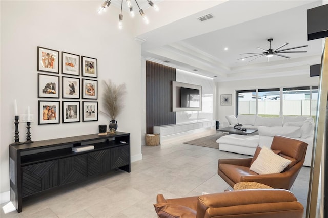 tiled living room with crown molding, a tray ceiling, and ceiling fan