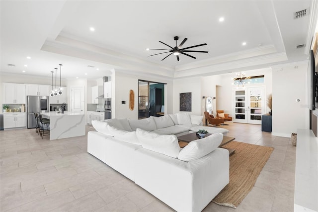 living room featuring light tile patterned flooring, ornamental molding, a chandelier, and a tray ceiling