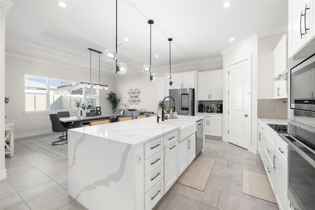 kitchen with light stone counters, an island with sink, and white cabinets