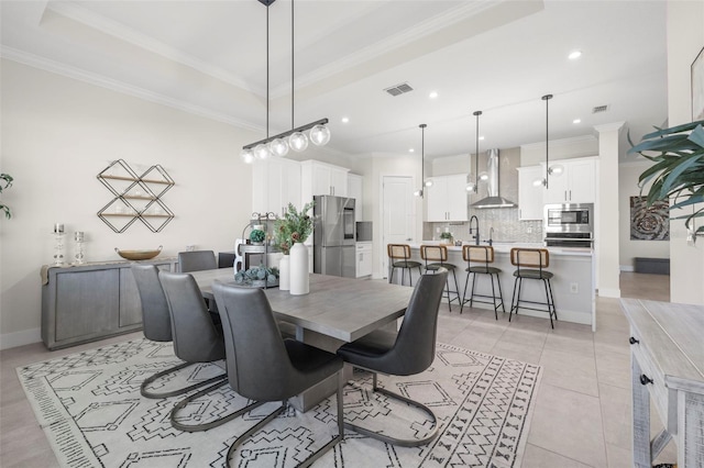 dining room with light tile patterned floors, a tray ceiling, ornamental molding, and sink