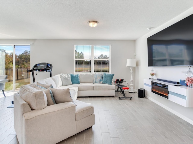 living room with a textured ceiling, light hardwood / wood-style flooring, and plenty of natural light