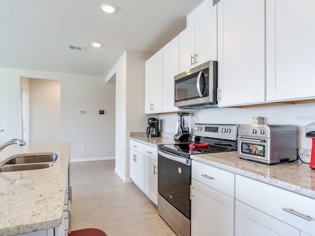 kitchen featuring sink, white cabinets, light stone countertops, and appliances with stainless steel finishes