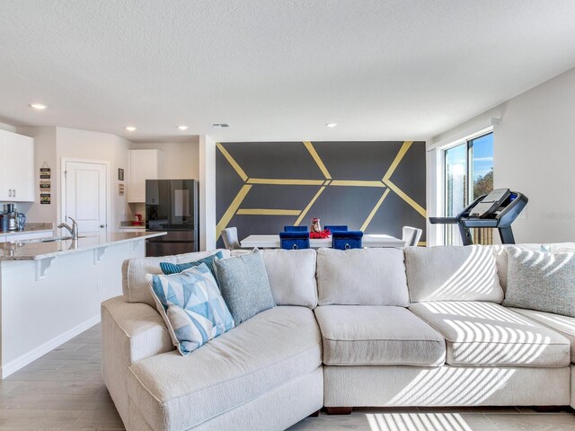 living room featuring sink, a textured ceiling, and light hardwood / wood-style flooring