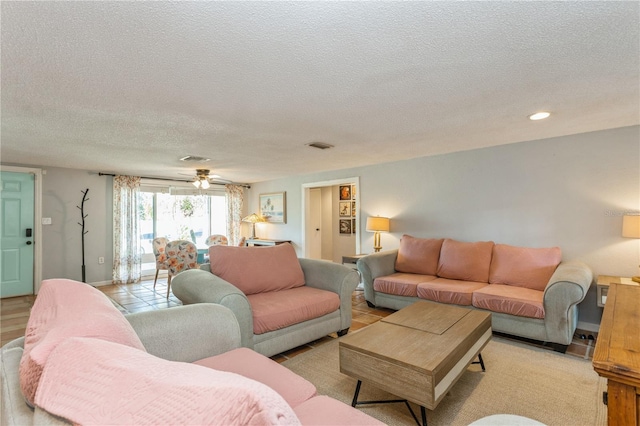 living room featuring ceiling fan and a textured ceiling