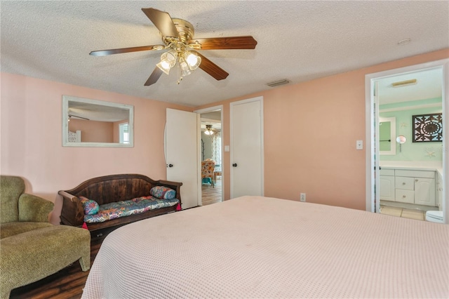 bedroom with ceiling fan, ensuite bathroom, and a textured ceiling