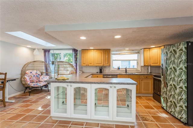 kitchen with kitchen peninsula, decorative backsplash, sink, a skylight, and black range with electric cooktop