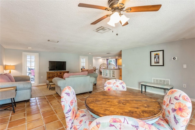 dining area with ceiling fan, light tile patterned flooring, and a textured ceiling