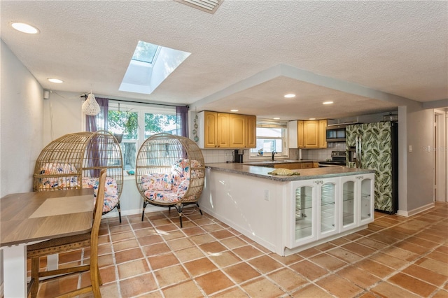 kitchen featuring kitchen peninsula, decorative backsplash, stainless steel appliances, and a textured ceiling