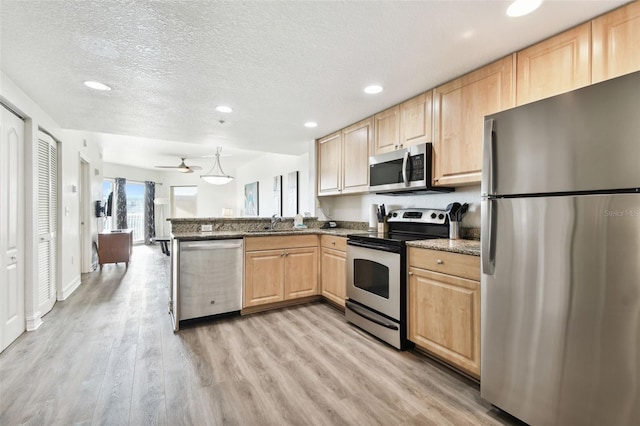 kitchen with kitchen peninsula, light brown cabinetry, stainless steel appliances, and light hardwood / wood-style floors