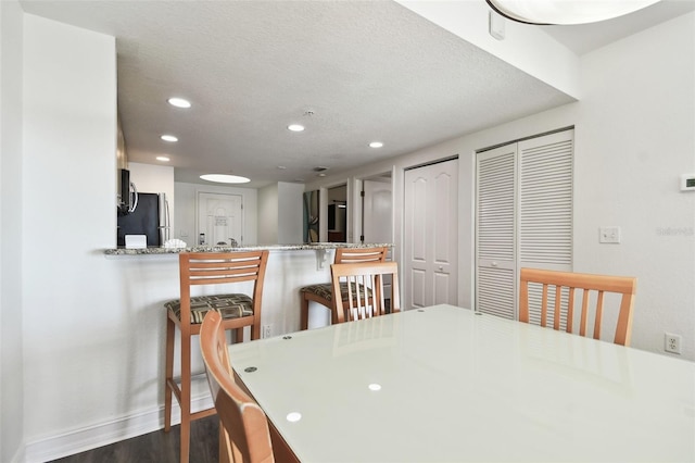 dining area with dark hardwood / wood-style flooring and a textured ceiling