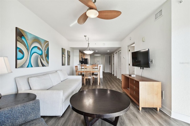 living room featuring wood-type flooring and ceiling fan