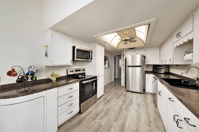 kitchen with light wood-type flooring, stainless steel appliances, ceiling fan, sink, and white cabinets