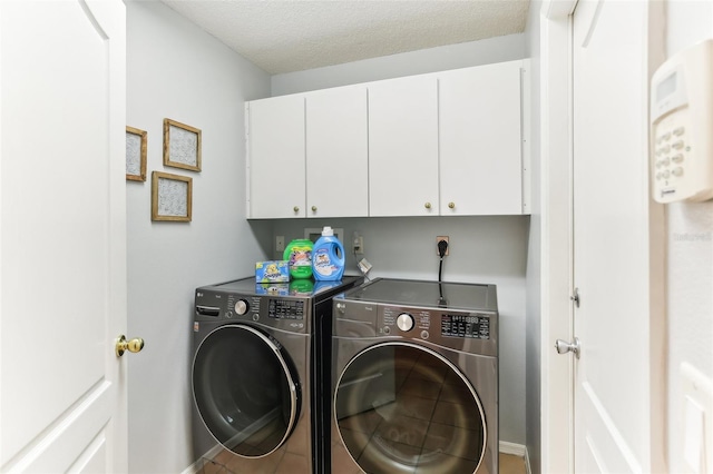 laundry room with cabinets, a textured ceiling, and washing machine and dryer