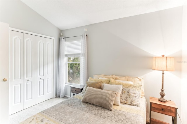 carpeted bedroom with a closet and lofted ceiling