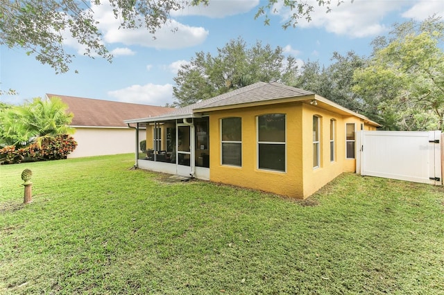 back of property with a sunroom and a yard