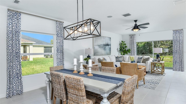 tiled dining room featuring ceiling fan with notable chandelier and plenty of natural light