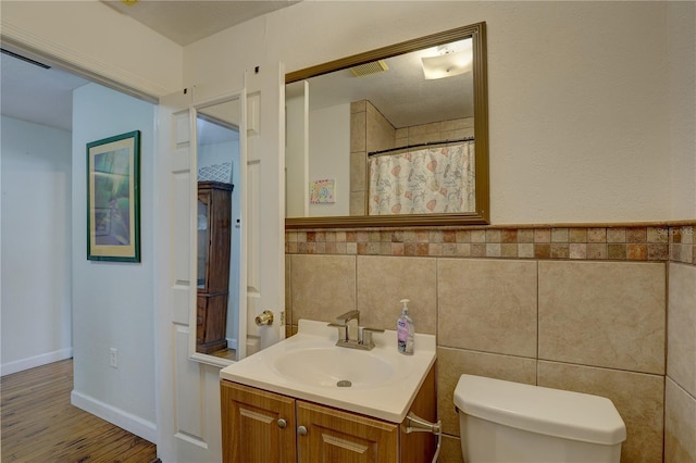 bathroom with vanity, hardwood / wood-style flooring, toilet, tile walls, and curtained shower