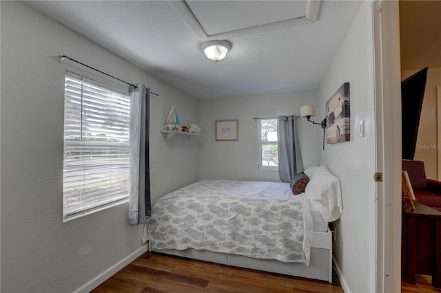 bedroom with dark hardwood / wood-style floors and multiple windows