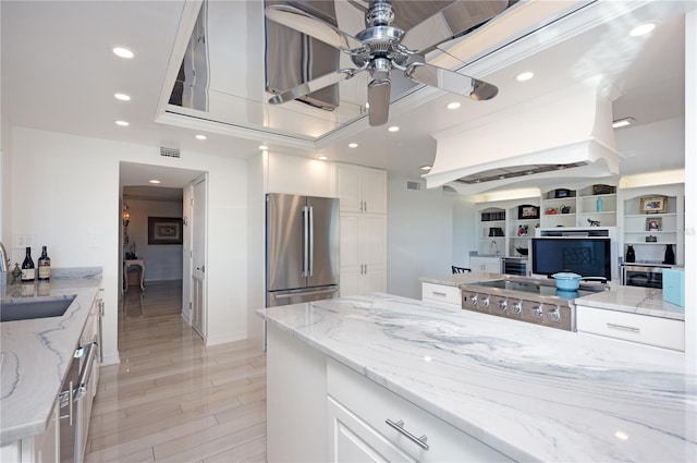 kitchen with white cabinetry, sink, stainless steel appliances, light stone counters, and light hardwood / wood-style flooring