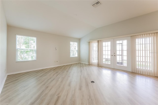 unfurnished room featuring french doors, a healthy amount of sunlight, vaulted ceiling, and light wood-type flooring