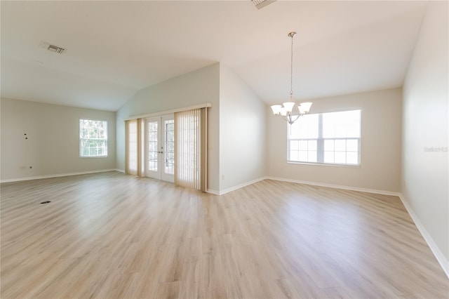 spare room with french doors, an inviting chandelier, vaulted ceiling, and light wood-type flooring