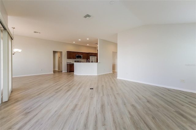 unfurnished living room with a notable chandelier and light hardwood / wood-style flooring