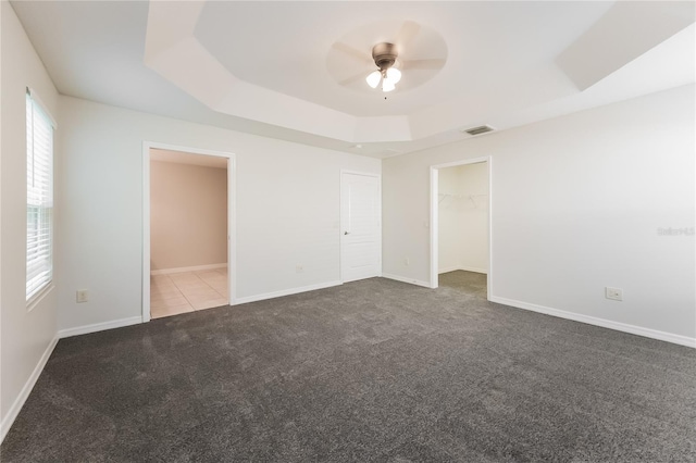 carpeted spare room featuring ceiling fan and a raised ceiling