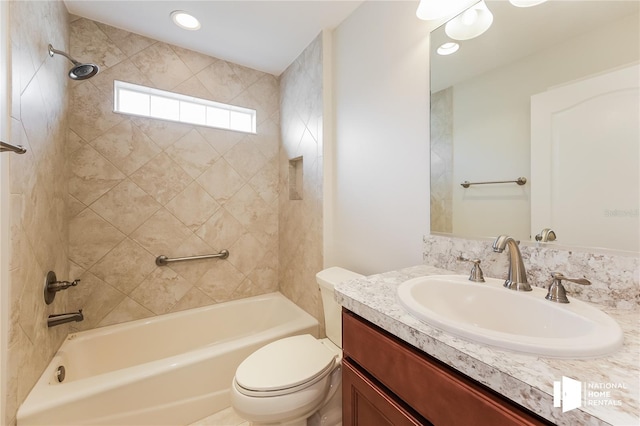 full bathroom featuring toilet, vanity, and tiled shower / bath