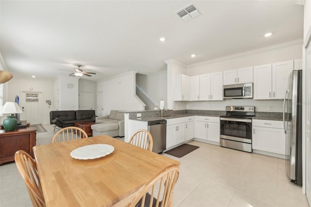 interior space featuring white cabinetry, stainless steel appliances, dark stone counters, sink, and ceiling fan