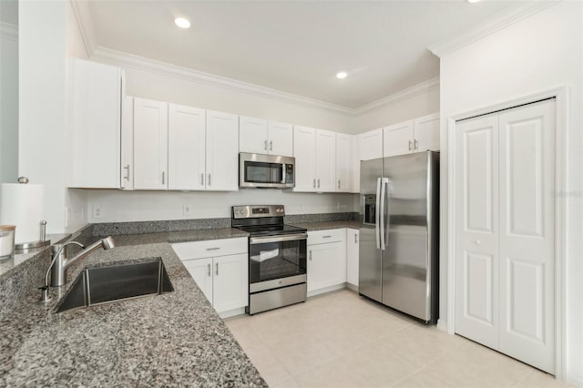 kitchen with stainless steel appliances, light tile patterned flooring, dark stone countertops, white cabinets, and sink