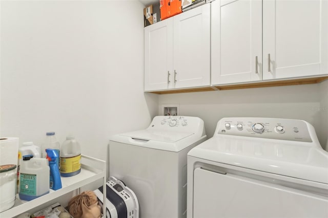 clothes washing area featuring washer and clothes dryer and cabinets