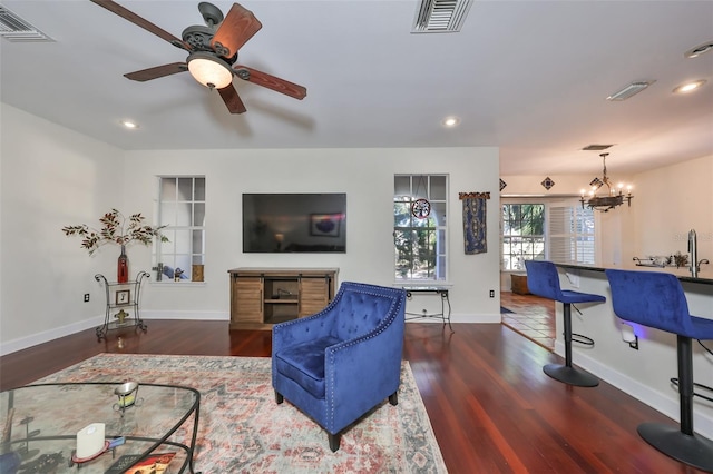 living room with dark hardwood / wood-style flooring and ceiling fan with notable chandelier