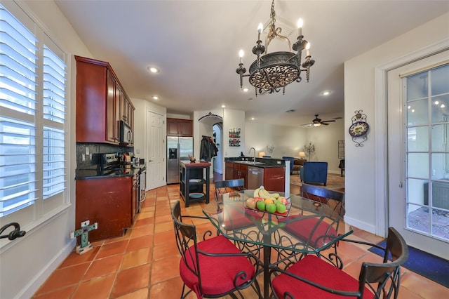 dining space featuring light tile patterned flooring, sink, and ceiling fan with notable chandelier