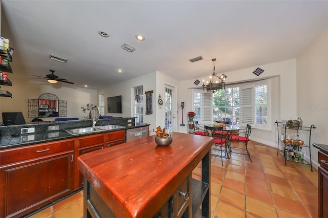 tiled dining space with sink and ceiling fan with notable chandelier