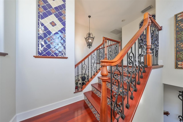 staircase with hardwood / wood-style flooring and a chandelier