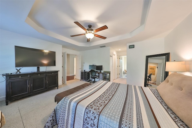 bedroom featuring ceiling fan, a tray ceiling, and light carpet