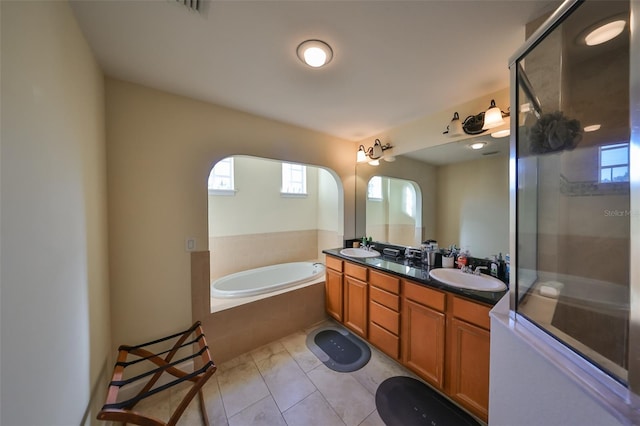 bathroom featuring a relaxing tiled tub, vanity, tile patterned flooring, and a wealth of natural light